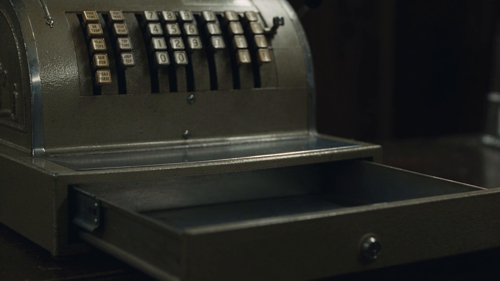An old cash register drawer slides open, empty, under a flickering fluorescent light.
